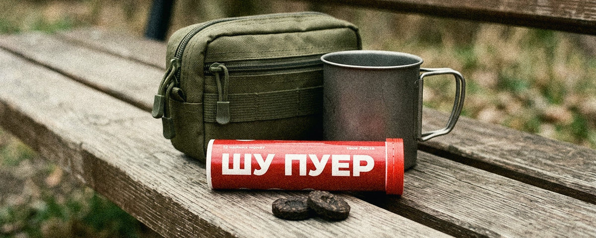 Чай у подарунок військовому: металева туба з пресованими чайними монетами, термос і кружка на дерев’яній поверхні
